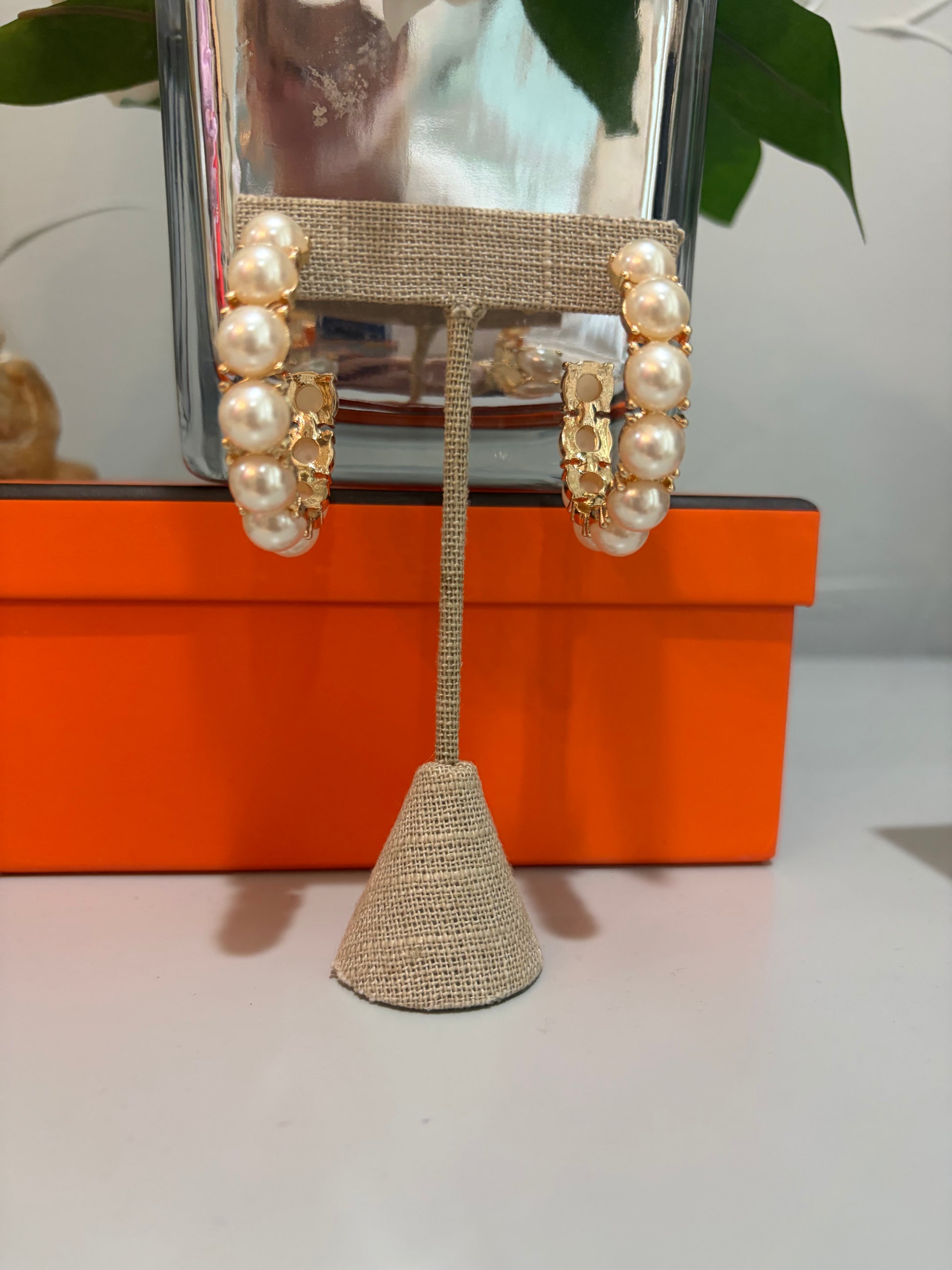 Pearl and gold earrings on a stand with an orange box in the background