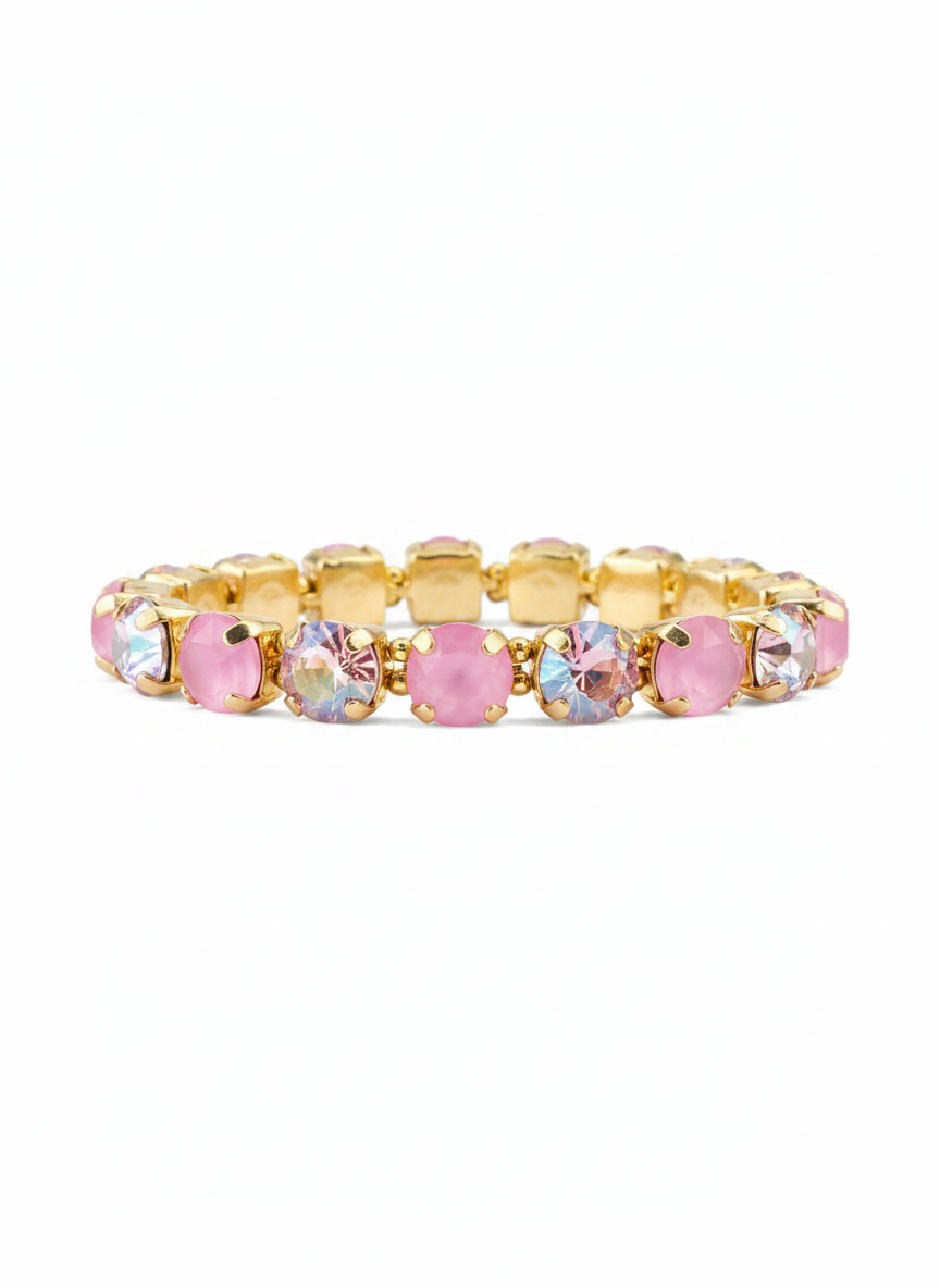 A gold-plated tennis bracelet featuring alternating round pink faceted crystals and oval iridescent clear crystals, displayed against a solid white background.