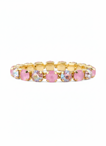 A gold-plated tennis bracelet featuring alternating round pink faceted crystals and oval iridescent clear crystals, displayed against a solid white background.