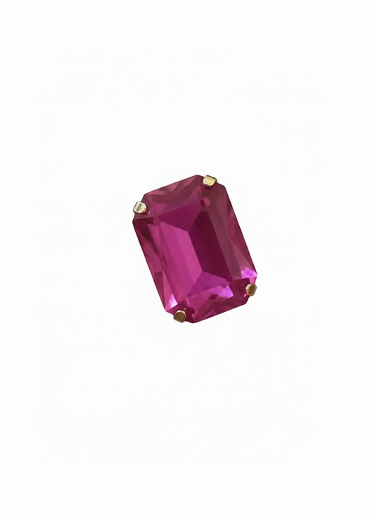 A rectangular emerald-cut magenta pink gemstone ring with small gold prongs, adjustable and water resistant  shown on a plain white background.