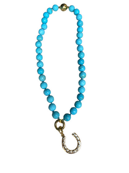 A turquoise beaded necklace with a gold horseshoe charm with magnetic closure and water resistant