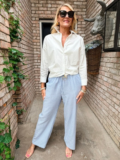 woman wearing white oxford top with a blue and white stripe flowy pant