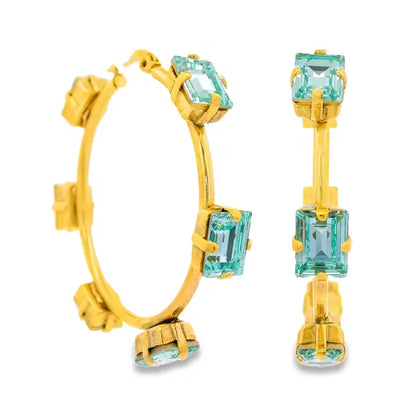 Gold hoop earrings with light blue gemstones on a white background