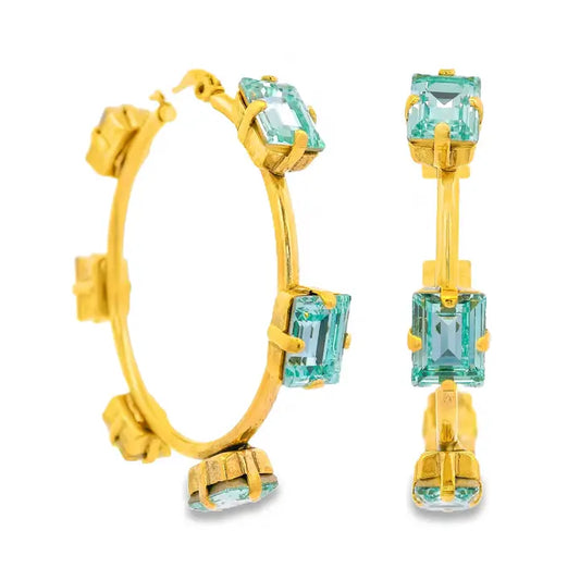 Gold hoop earrings with light blue gemstones on a white background