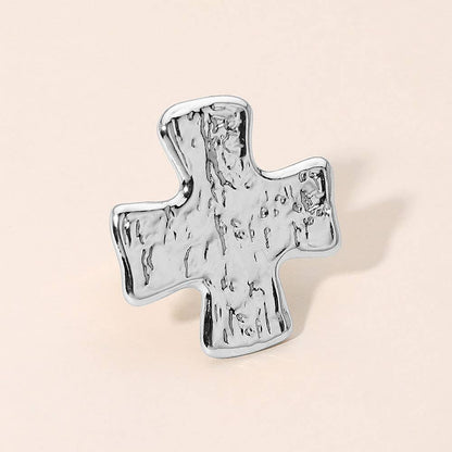 A silver cross-shaped ring with a textured, hammered finish 