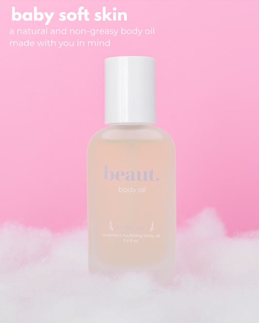 A frosted bottle of beaut. body oil with a white cap, set against a soft pink background with white fluffy clouds at the bottom and promotional text in the upper left.