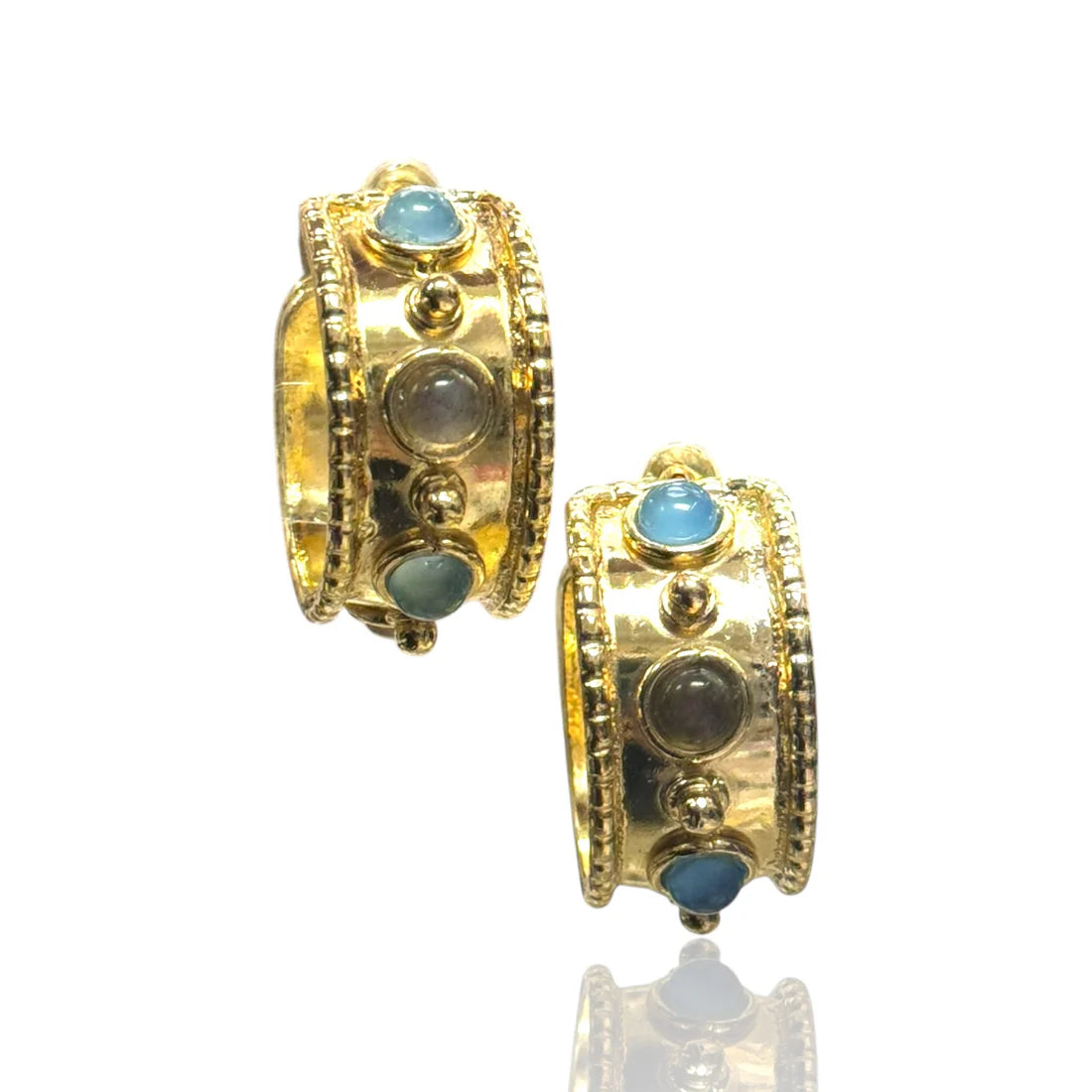 Gold hoop earrings with blue gemstones on a white background