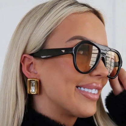woman wearing gold earrings with a crystal stone in the middle. water resistant