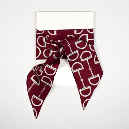 A burgundy silk scarf with a white horse bit pattern