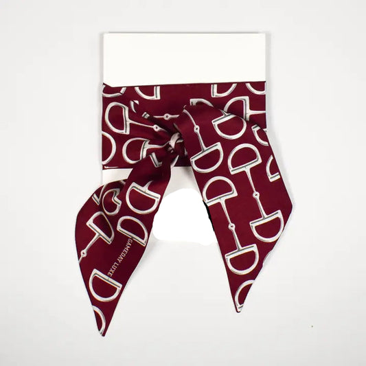 A burgundy silk scarf with a white horse bit pattern