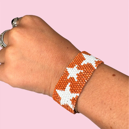 a woven cuff bracelet in orange and white with a star pattern