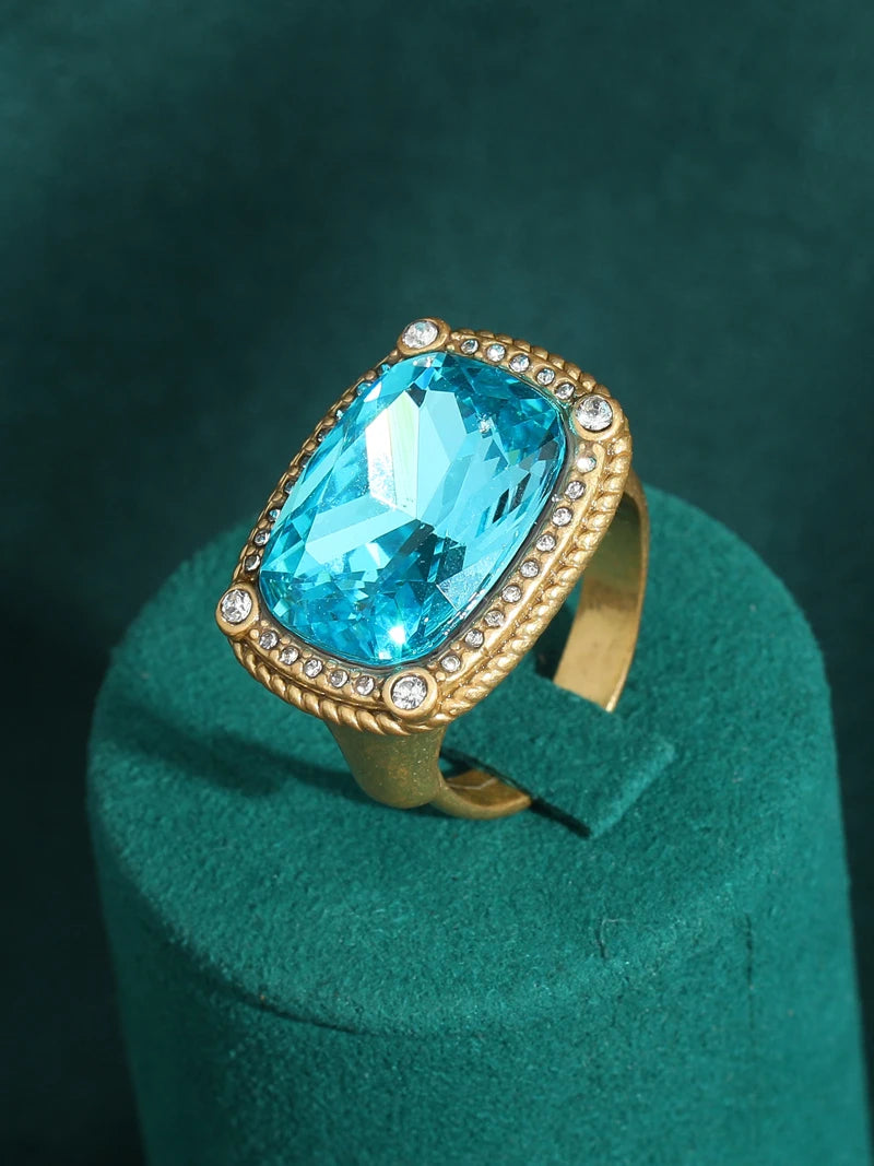 blue stone ring set in a gold band surrounded by rhinestones, adjustable band