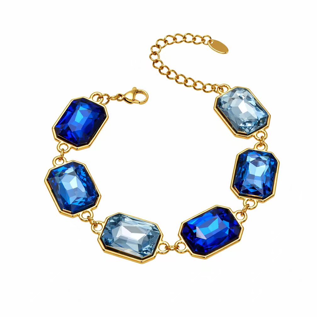 A gold-tone chain bracelet featuring alternating rectangular blue and light blue faceted rhinestones, displayed on a clean white background. 