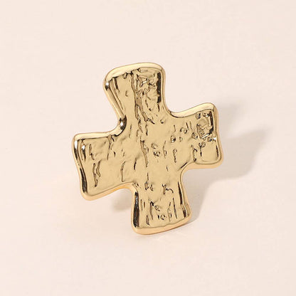 A textured gold cross-shaped ring with a hammered finish