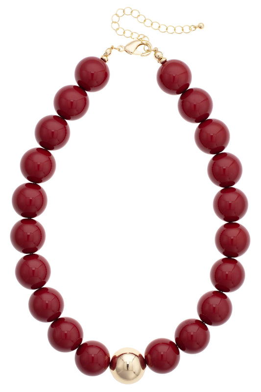burgundy/crimson beaded necklace with a gold clasp and one gold bead. 