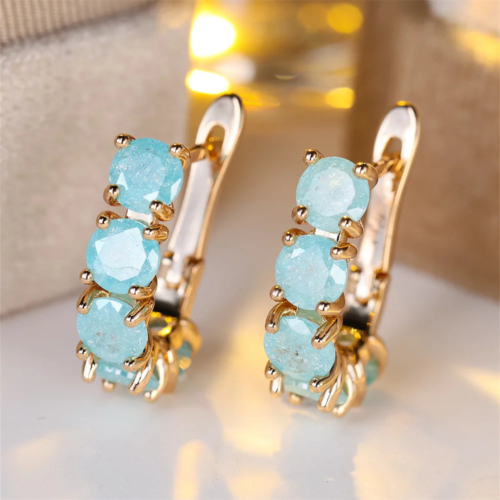 Gold earrings with turquoise stones on a soft background