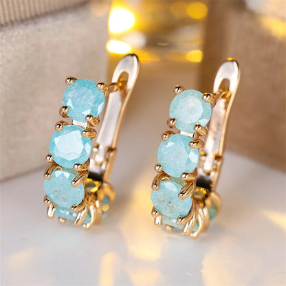 Gold earrings with turquoise stones on a soft background