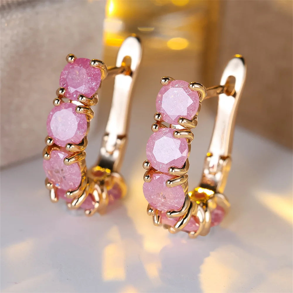 Gold hoop earrings with pink gemstones on a soft background