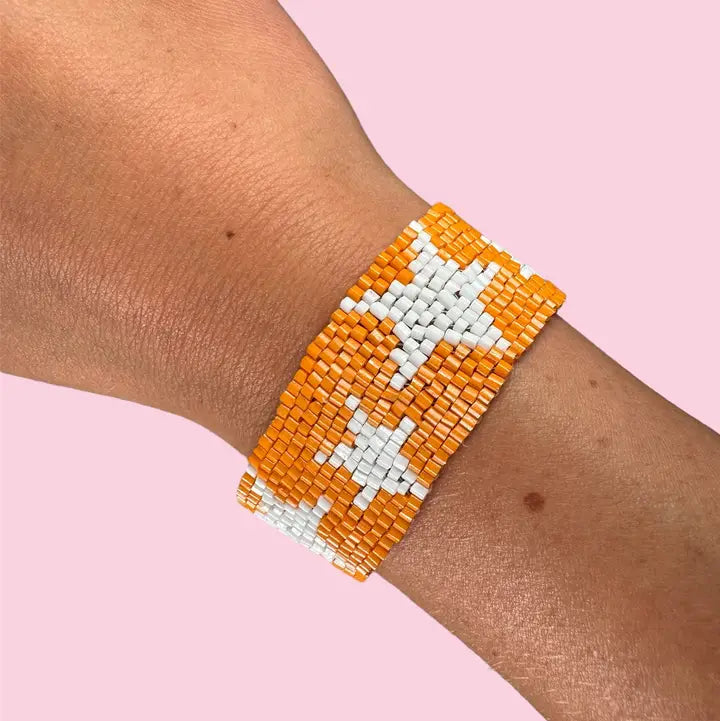 A beaded wrap bracelet with a star pattern of orange and white beads, 