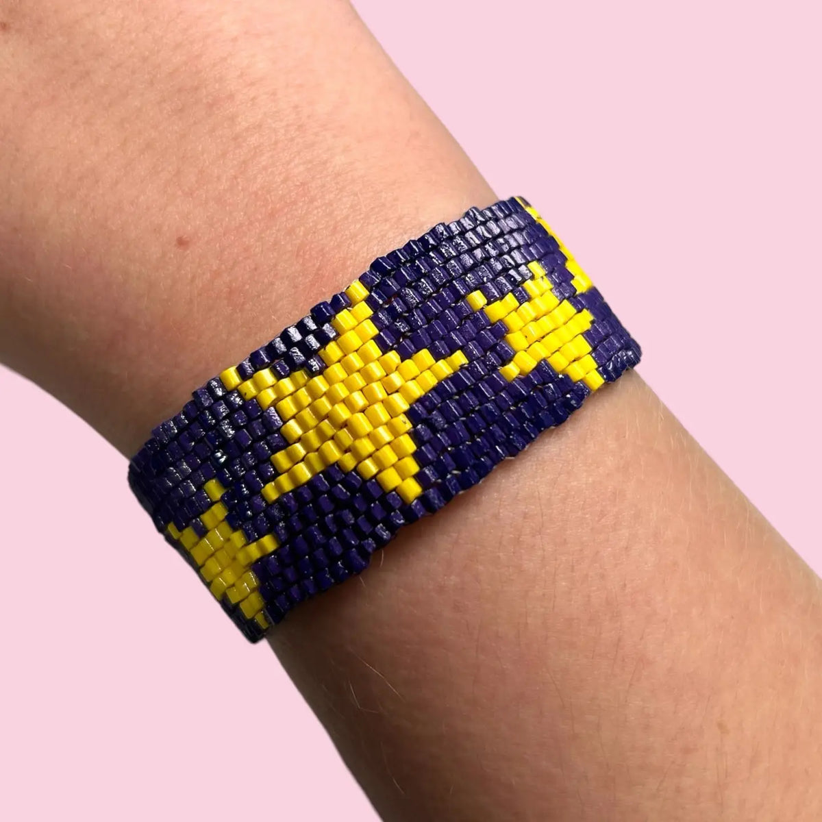 A beaded wrap bracelet in purple featuring stars in gold/yellow color