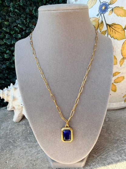 Gold link necklace with a blue rhinestone pendant on a mannequin bust.