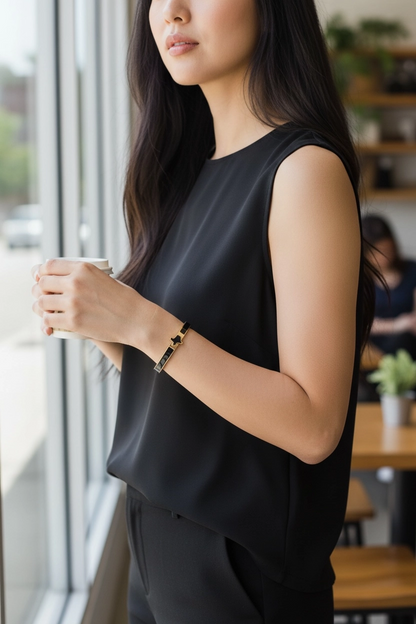 woman wearing black and gold enamel bangle bracelet with black enamel shaped texas detail