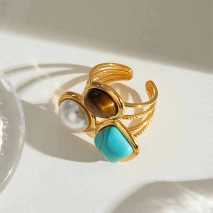 a stainless steel adjustable gold ring with 3 stones .. pearl, tiger eye and turquoise.