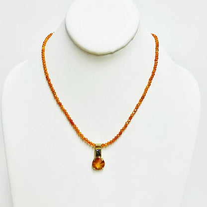 tova vira neckalce with small orange beads with a pendant in oval orangish colored gemstone
