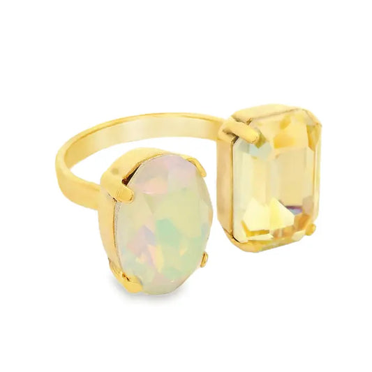 A gold ring featuring two large oval-cut stones, one with a pale iridescent opalescent sheen and the other a yellow emerald-cut stone, set against a plain white background.