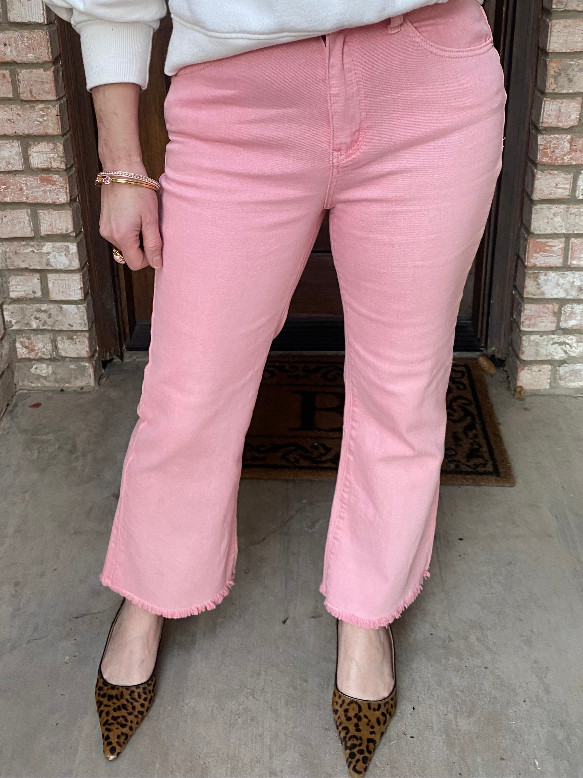 Person wearing pink pants and a white top sitting on a step.